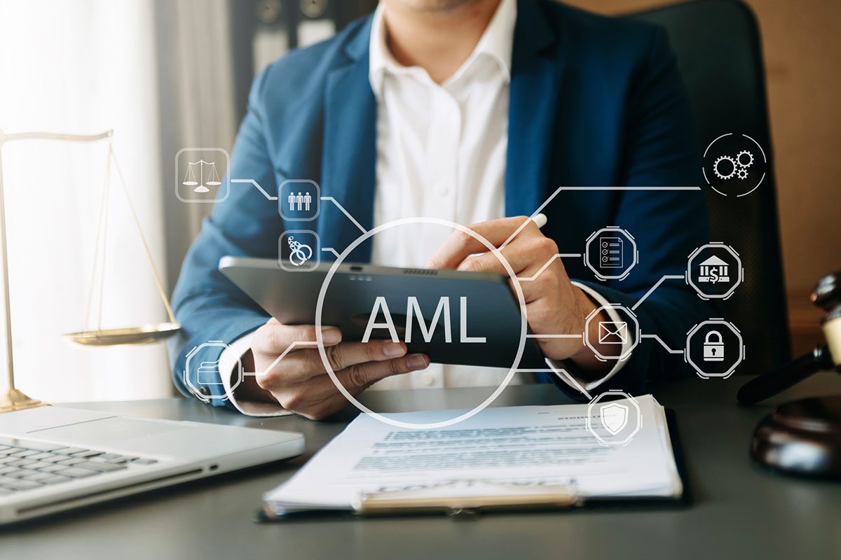 A person in a suit uses a tablet at a desk with legal documents, a justice scale, and AML (Anti-Money Laundering) icons displayed digitally.